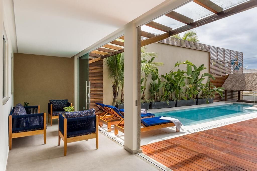 A modern outdoor pool area with wooden deck, lounge chairs, and potted plants.
