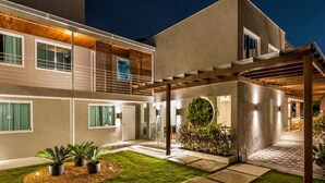 Uma casa moderna com alpendre coberto, gramado bem cuidado e um jardim circular.