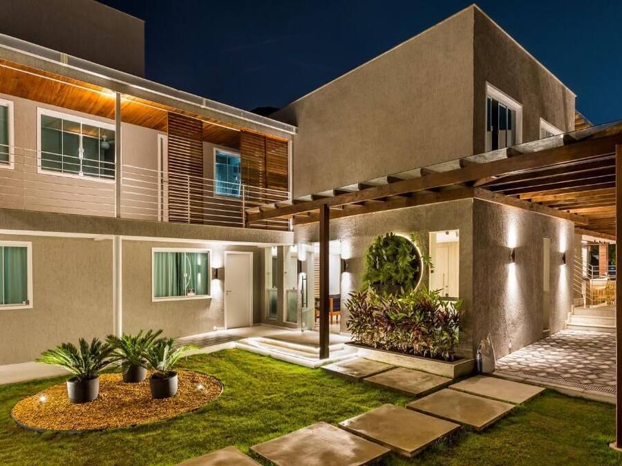 Ein modernes Haus mit überdachter Terrasse, einem gepflegten Rasen und einem kreisförmigen Garten.