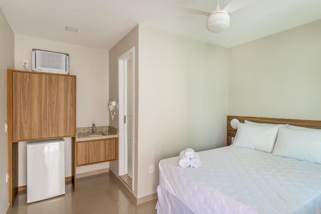 Une chambre avec un lit, un petit coin cuisine et un ventilateur de plafond.