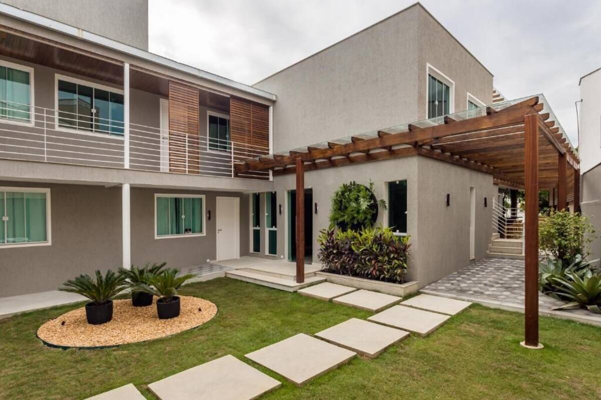 A modern two-story house with a covered patio, a small garden, and a staircase leading to the upper floor.