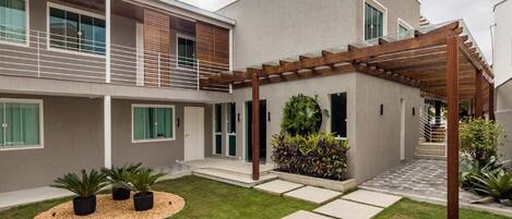 A modern two-story house with a covered patio, a small garden, and a staircase leading to the upper floor.