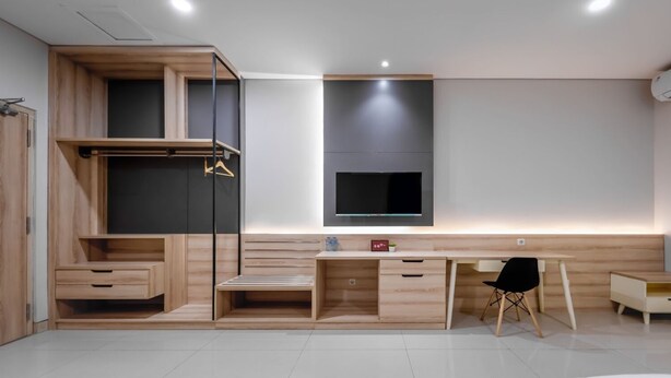Une chambre moderne équipée d’un bureau intégré, d’un lit et d’une armoire.