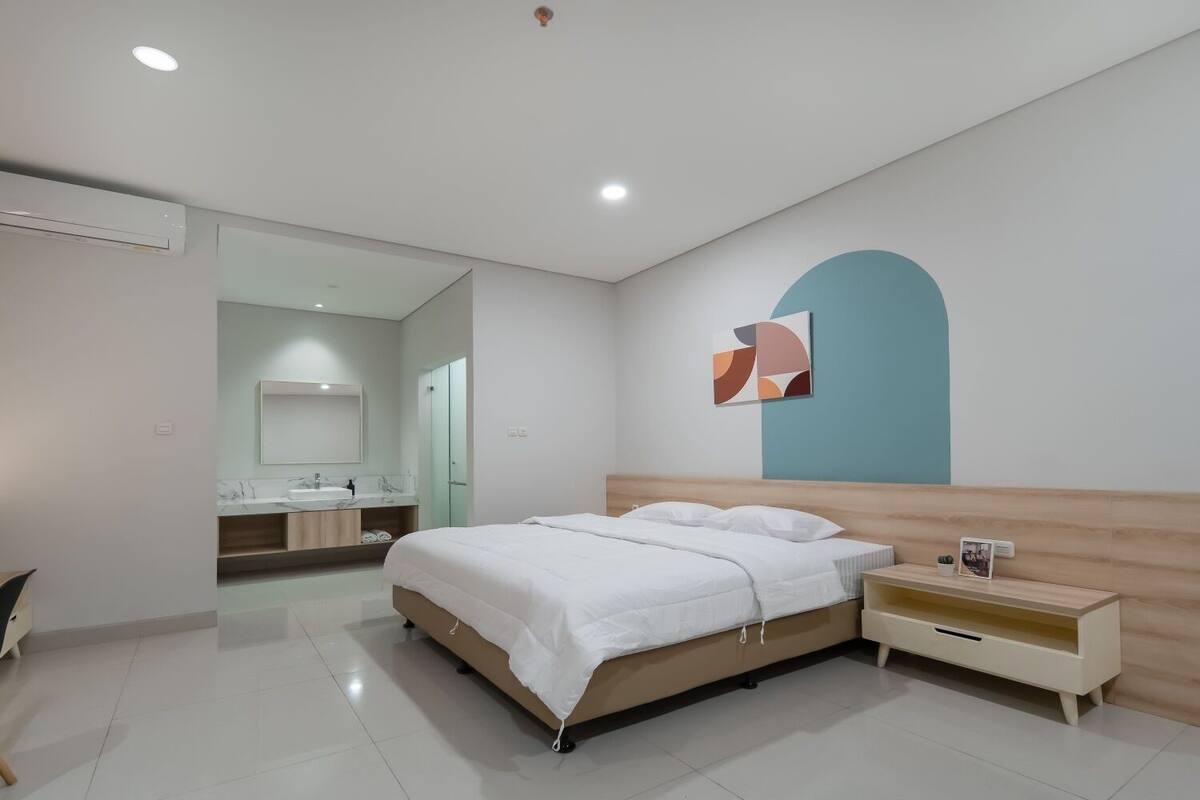 A modern bedroom with a bed, bedside table, and a wall-mounted artwork.