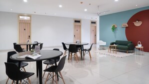 Une salle de conférence moderne, dotée de tables rondes, de chaises noires et d’un canapé vert.