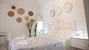 A bedroom with a bed, bedside tables, a mirror, and wall decorations. - Holyday Home in Historic Center very close ti Porta Vecchia Beach  (Monopoli)