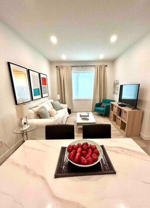 A modern living room with a dining area, a sofa set, a TV, and artwork on the walls. - Nest in the City - close to The Forks & Downtown
 (Winnipeg)