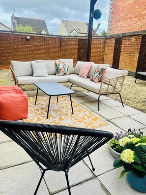 Eine Terrasse mit einer Couch, einem kleinen Tisch und einem Stuhl.