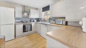 Une cuisine moderne avec des meubles blancs, un four encastré et un four à micro-ondes.
