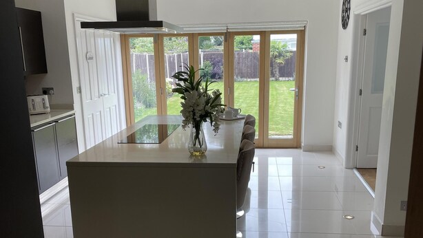 A modern kitchen with a central island, a built-in oven, and a large window.