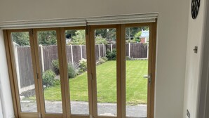 A room with a large sliding glass door leading to a backyard with a wooden fence and grass.