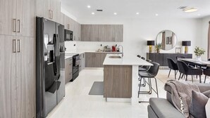 A modern kitchen with a central island, built-in appliances, and a dining area with a round table and chairs. - Avi Lux Stay (Miami)