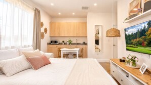 A bedroom with a large bed, a dining table, and a kitchen area in the background. - Avi Lux Stay (Miami)