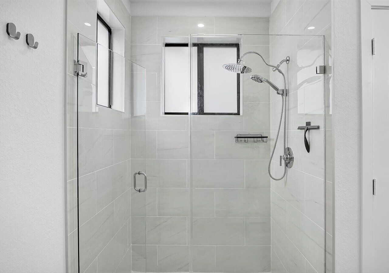 A modern shower with a glass enclosure, a window, and a handheld showerhead.