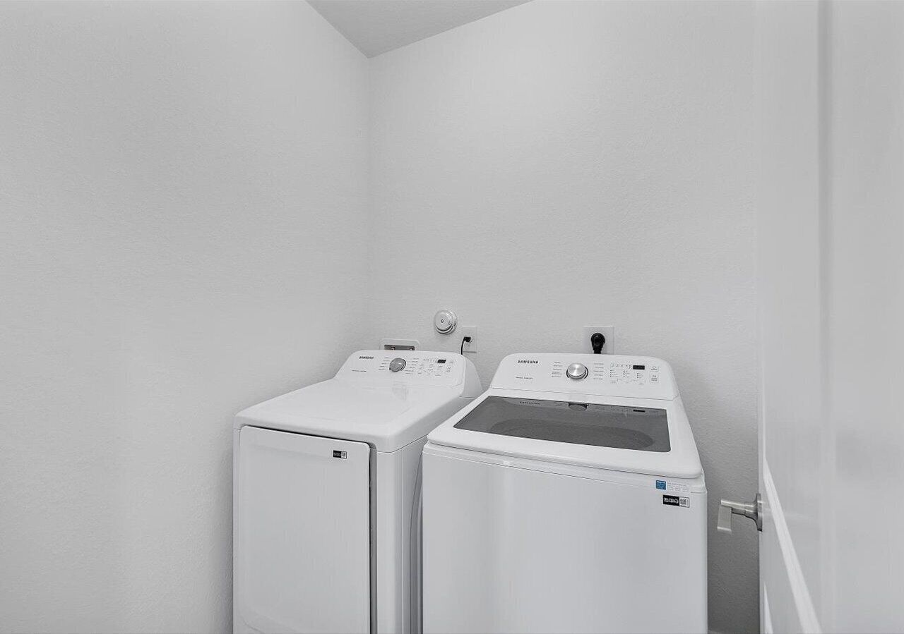 A laundry room with two white washing machines and a dryer.