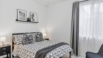 A bedroom with a bed, bedside tables, a chair, and a window with curtains.