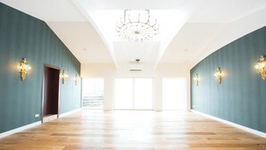 A spacious hallway with wooden flooring, teal walls, and a chandelier. - DORMERO Hotel Aalen (Aalen)