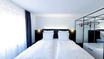 Una habitación de hotel con cama, mesita de noche, espejo y armario.