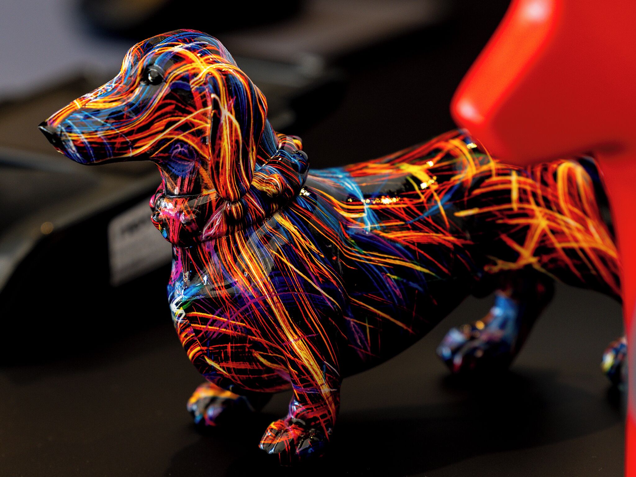 A colorful dog figurine with a red background.