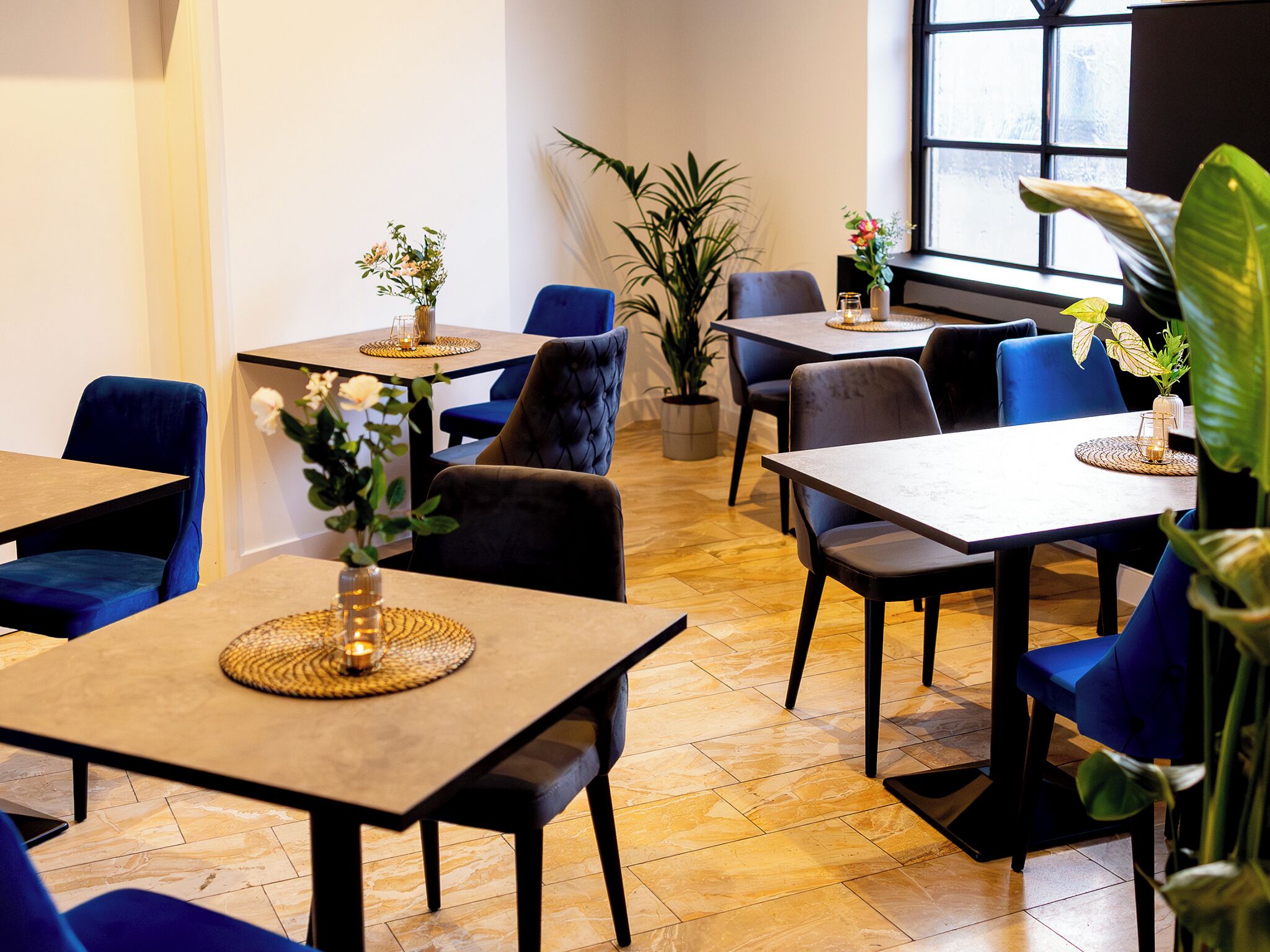 A dining area with tables, chairs, and potted plants.