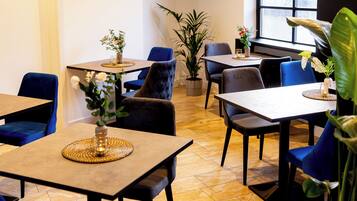 A dining area with tables, chairs, and potted plants.