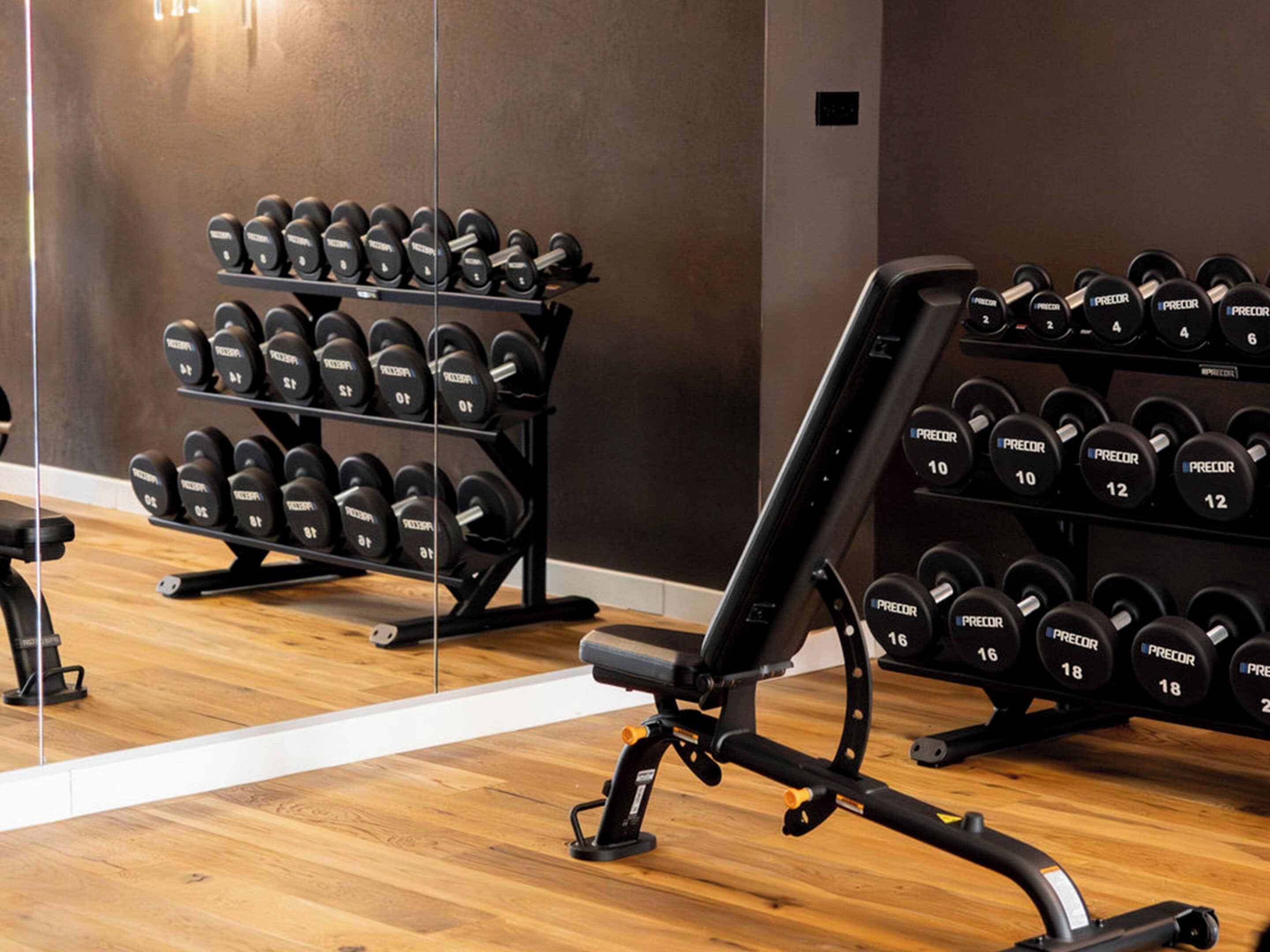 A gym with weight racks, benches, and dumbbells.