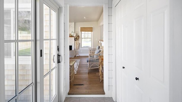 A hallway with a view into a dining area, featuring wicker furniture and a window. - Edgartown Village Home w/ Pool. 
4bdrm / 3.5bth (Edgartown)