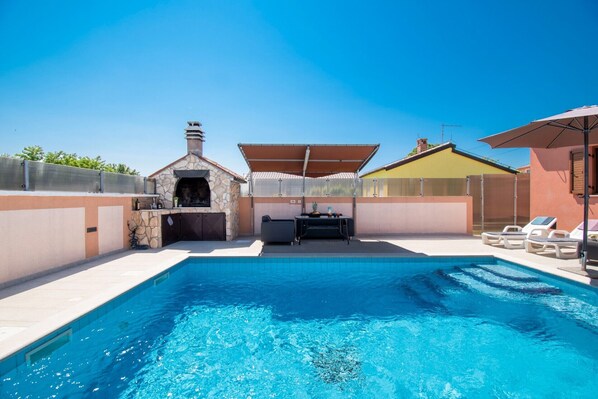 Relax by the pool surrounded by a deck, lounge chairs, and umbrellas.