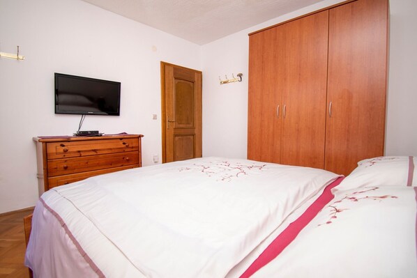 A bedroom with a bed, wooden dresser, television, and wardrobe.
