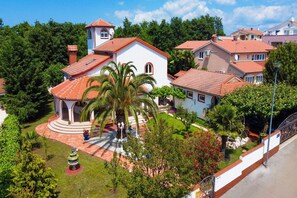A residential area with multiple houses, a central white building with a red roof, and a small tower.