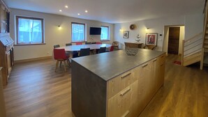 A spacious kitchen with a large island, wooden cabinets, and a dining area with a long table and chairs.