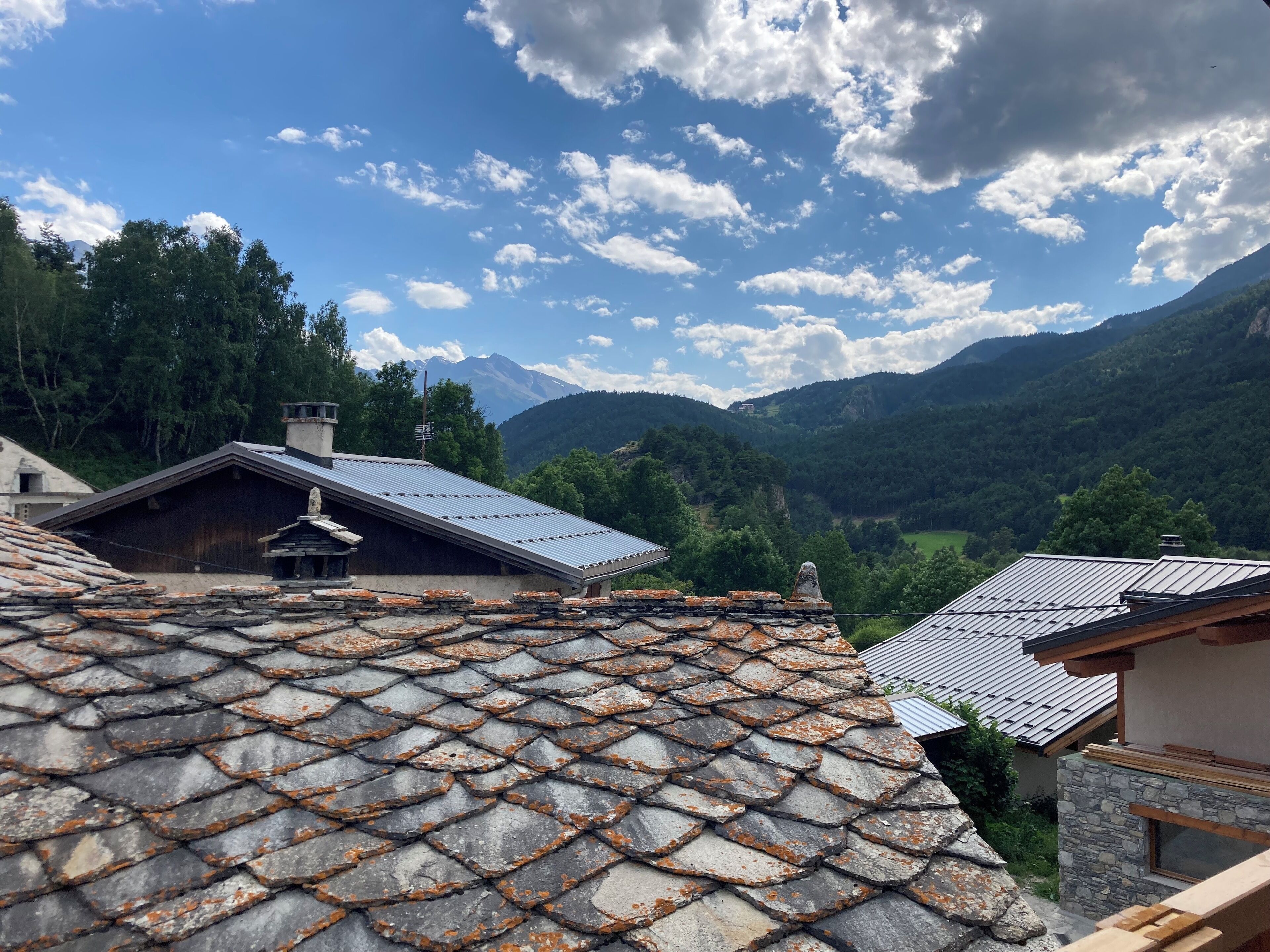 Un paysage montagneux, avec des bâtiments traditionnels aux toits de pierre et un ciel dégagé.