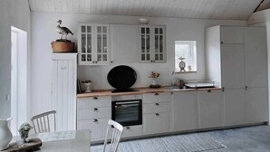 A kitchen with white cabinets, a black oven, and a wooden countertop. - Cozy house in small village near the sea (Skåne län)