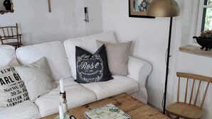 A cozy living room with a white sofa, a wooden coffee table, and a framed portrait on the wall. - Cozy house in small village near the sea (Skåne län)