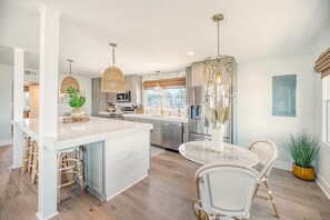 Enjoy meals at the central island with bar stools, a round dining table, and pendant lighting.