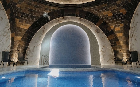 A swimming pool with a circular brick ceiling and arched windows.