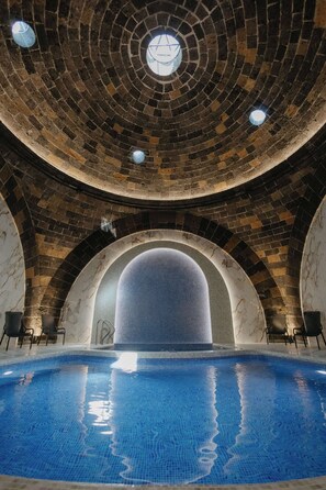 Une piscine dotée d’un plafond circulaire en briques et de fenêtres en arc de cercle.