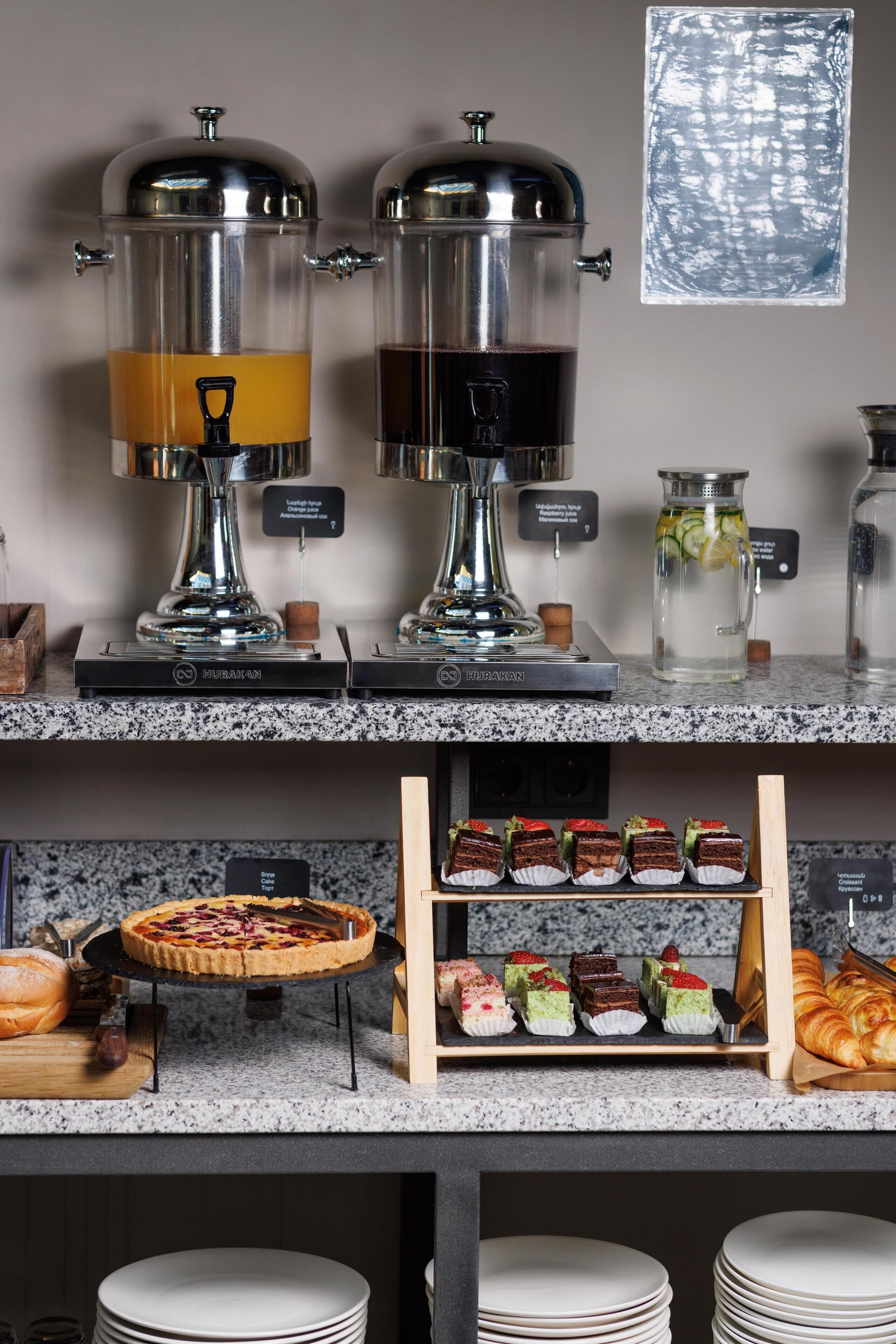 A buffet setup with two coffee dispensers, a pie, assorted desserts, and a croissant display.