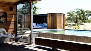 Ein moderner Außenbereich mit Pool, Holzterrasse und Blick auf eine natürliche Landschaft.
