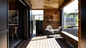 Ein modernes Interieur mit Holzdeck, einem weißen, flauschigen Sessel und einer Essecke mit Tisch und Stühlen.