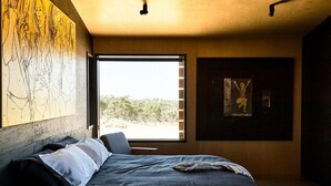 Ein Schlafzimmer mit einem großen Bett, einem Fenster mit Blick auf Bäume und einem Bild an der Wand.