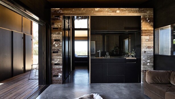 Ein modernes Interieur mit Holzboden, einem Fellteppich, einer Küchenzeile mit Spüle und Schränken sowie einem großen Fenster.