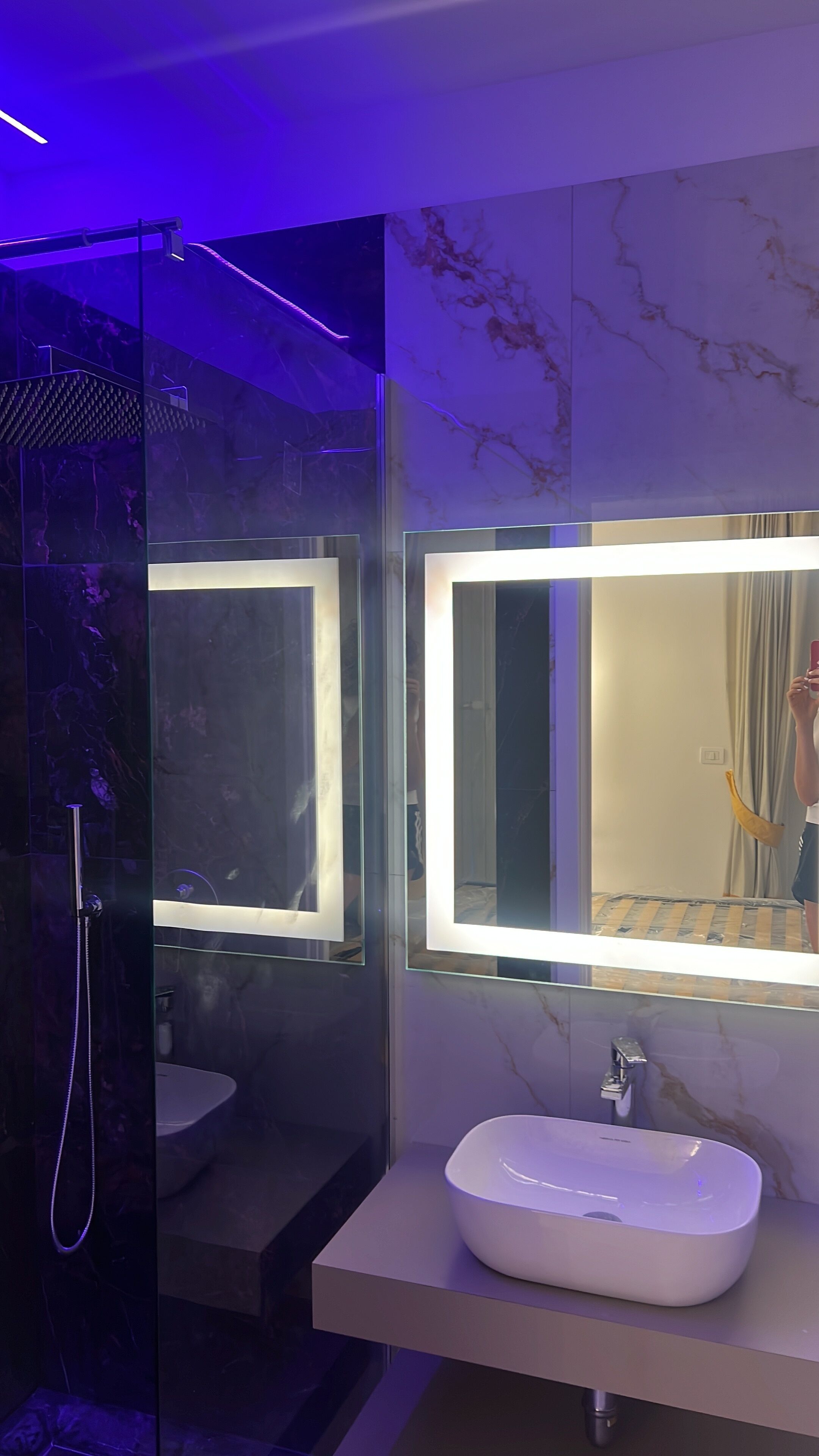 A modern bathroom with a glass-enclosed shower, a white sink, and a marble backsplash.