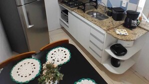 Kompakti keittiö, jossa on jääkaappi, liesi, pesuallas ja laatoitettu välitila.