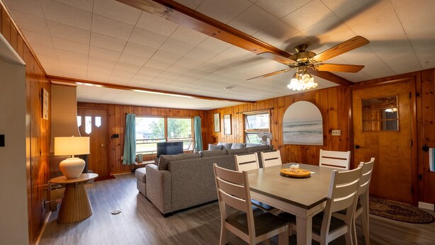 L’intérieur chaleureux d’un chalet comprend un coin repas, un canapé et un ventilateur de plafond.