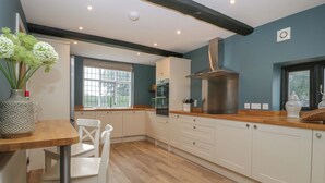 Une cuisine moderne avec des armoires blanches, un plan de travail en bois et une grande hotte en acier inoxydable.