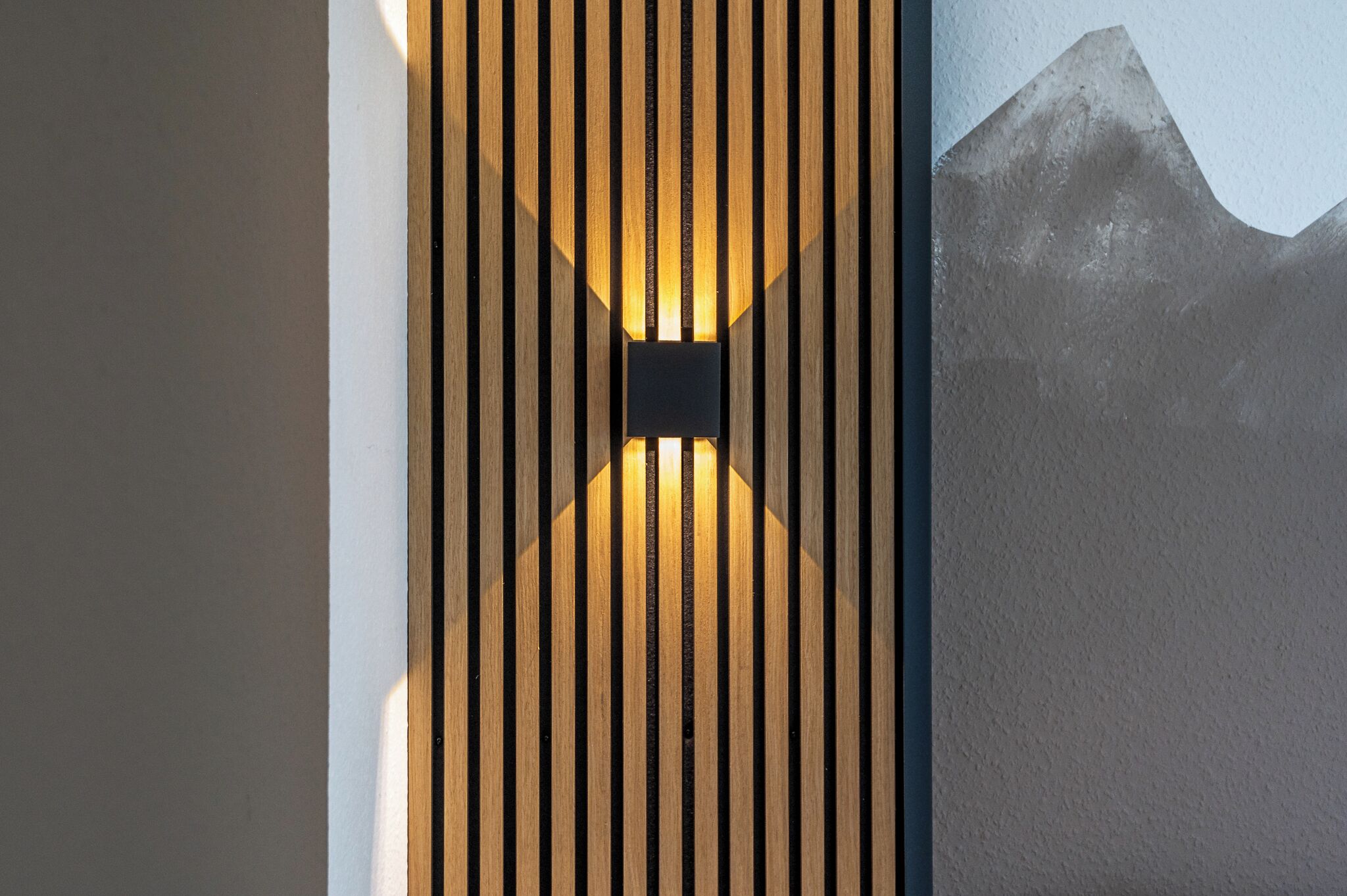 Eine Wand mit vertikalen Holzleisten und einem Bilderrahmen mit einem Bergmotiv.