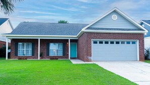A two-story house with a brick facade, a front porch, and a garage. - Foley Vacation or Monthly Stay Near OWA | Sleeps 12 (Foley)
