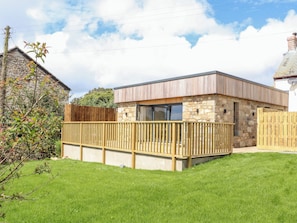 A modern house with a stone facade, a wooden deck, and a clear sky.