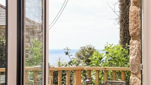 Ein Balkon mit Meerblick, einem Hollerleger und einem Metallstuhl.